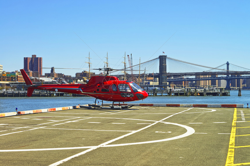 直升机从美国纽约曼哈顿下城东河的直升机停坪起飞6号码头背景中的布鲁克林大桥图片