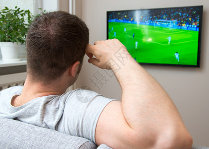 男人在家看电视上的足球比赛图片