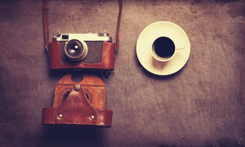 白色的咖啡杯和复古相机在灰色背景的皮套图片
