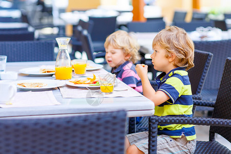 两个小男孩在酒店餐厅或城市咖啡馆享用健康早餐有趣的孩子吃蔬菜和喝果汁图片