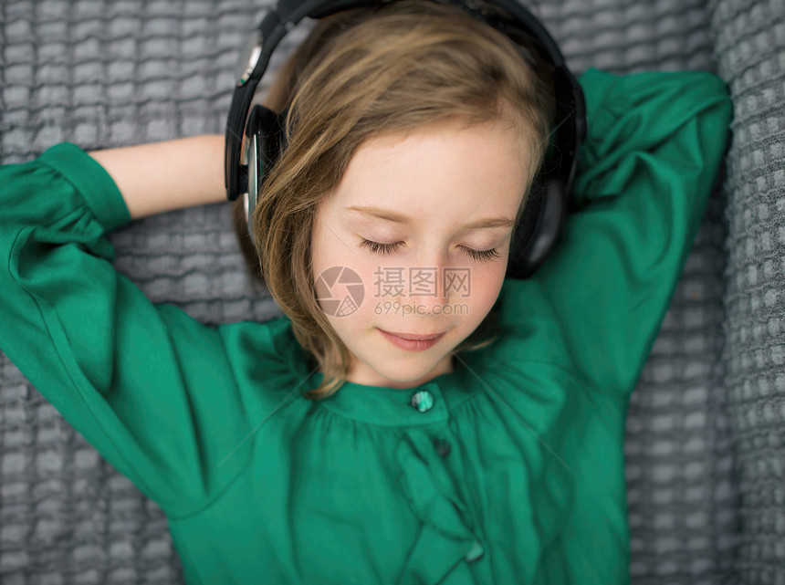 小女孩在耳机里听音乐图片