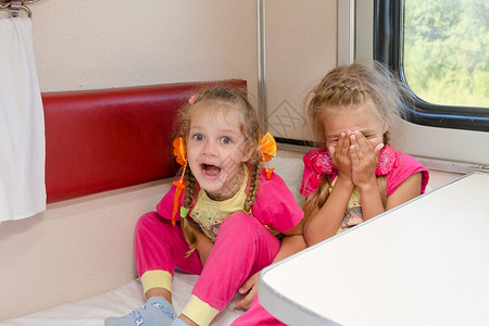 两个快乐的小女孩坐在火车上坐在低二等车图片