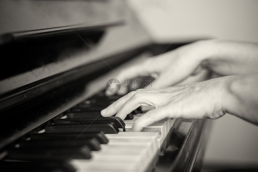 两只手弹钢琴的特写浅焦点黑与白图片