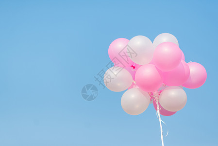 蓝色天空上的粉色和白色气球背景图片