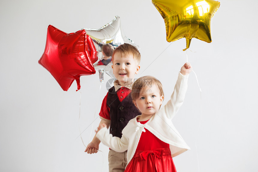 小孩子们拿着星形式的气球孩子们拿着一个星形气球快乐的孩子们在白色背景下带着五颜六色图片