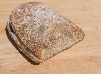 一块不健康的自制发霉面包放在棕色木板上图片