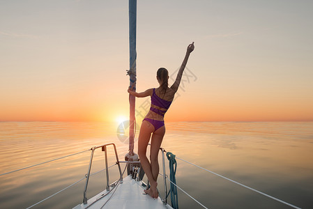 站在游艇弓上的女孩游艇上的女士举手加勒比海的日出比以往任图片