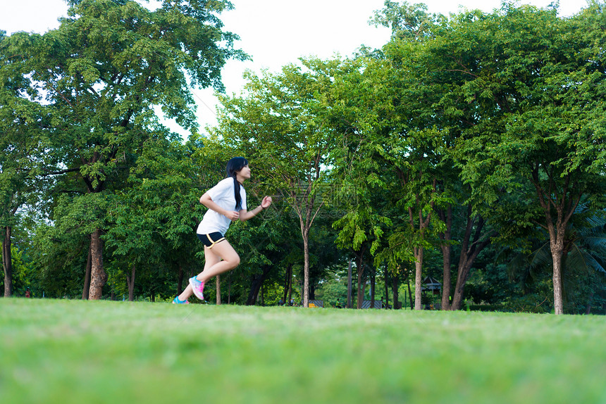 在绿草公园跑的年轻健身女子图片
