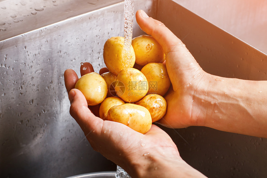 人手洗土豆水流下的新土豆健康汤的营养在农民市场购买图片