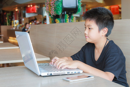 亚洲男孩在食堂使用笔记本电图片