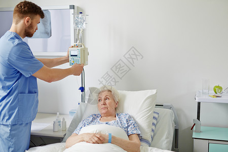 老妇人躺在医院的床上她的医生正在照顾她图片
