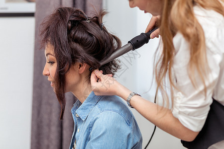 专业美发师在专业美发沙龙的背景下为年轻女做发型图片