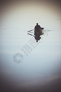 一个人在小船上划着小船在湖河上划桨河流有光滑的镜面水天气安静图片