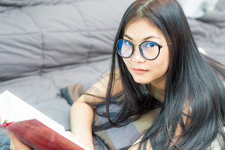 亚洲眼镜可爱的女在家床上看书教图片