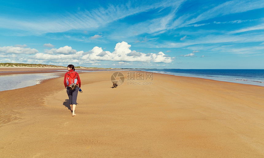 与他们的狗一起独自走在荒无人烟的海滩上诺森伯兰图片