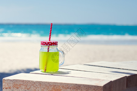 海边线附近的一杯绿色果汁背景图片