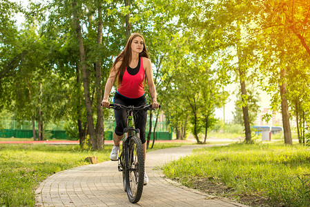 快乐的女孩骑自行车骑在公园外面的一辆山地自行车上图片