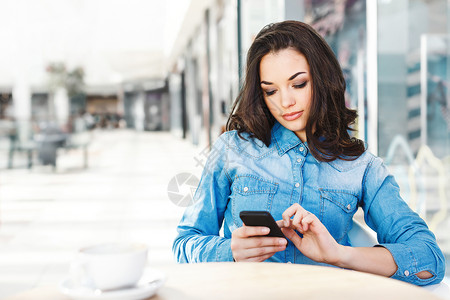 美丽的女孩坐在购物中心的咖啡馆里图片
