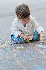 小男孩在街上用粉笔跳房子图片