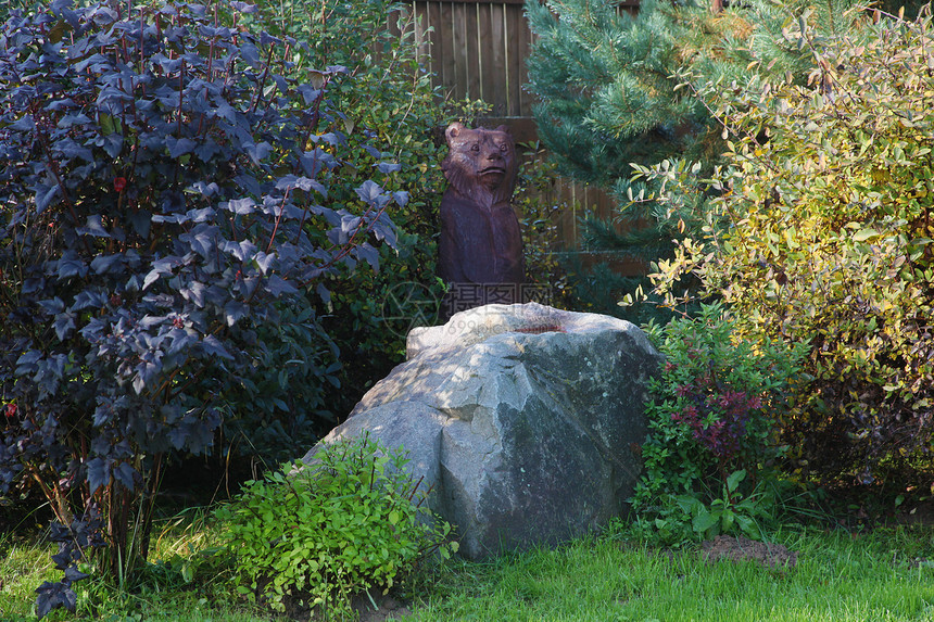 绿色花园中一只熊的木雕图片