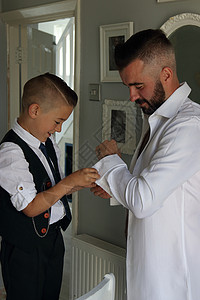 一个年轻男孩在结婚日给父亲穿衣服图片