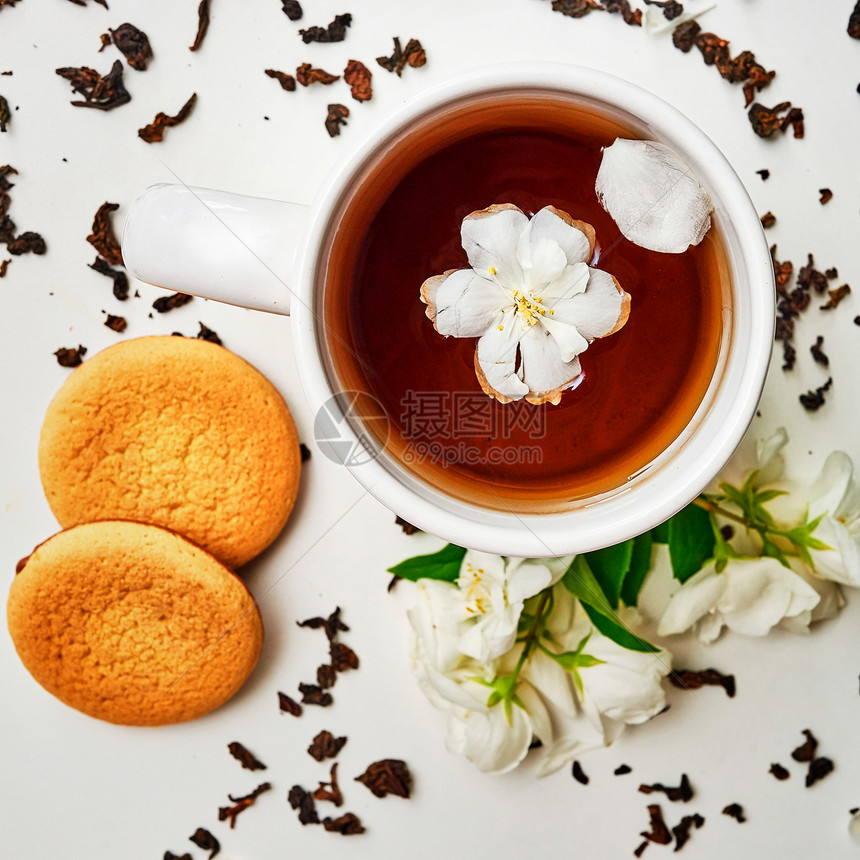 茶杯有干叶鲜香茉莉花和白色背景的饼干图片