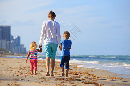 父亲和两个孩子在海滩上散图片