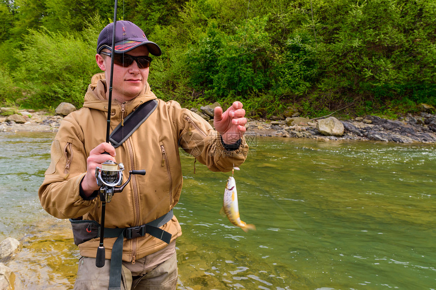 一位渔夫在山区河流上钓到了鳟鱼图片