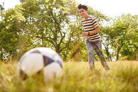 年轻的小孩在公园踢足球图片