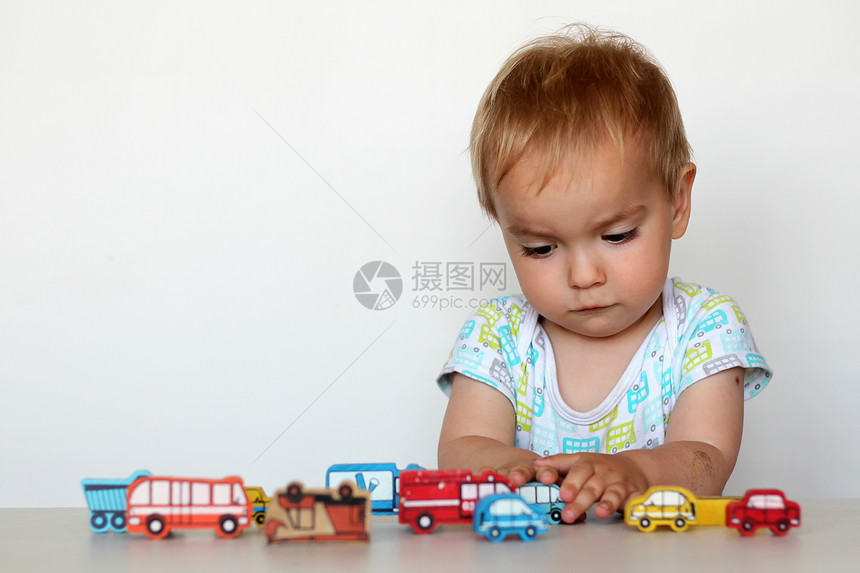可爱的蹒跚学步的男孩玩木制玩具车图片
