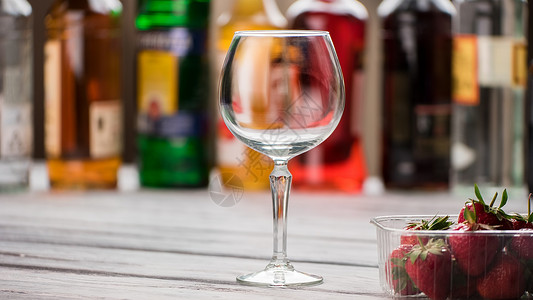 空的葡萄酒杯和草莓容器里的啤酒吧的木制桌子图片