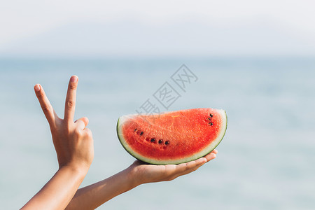 女孩在海边拿着一块西瓜图片