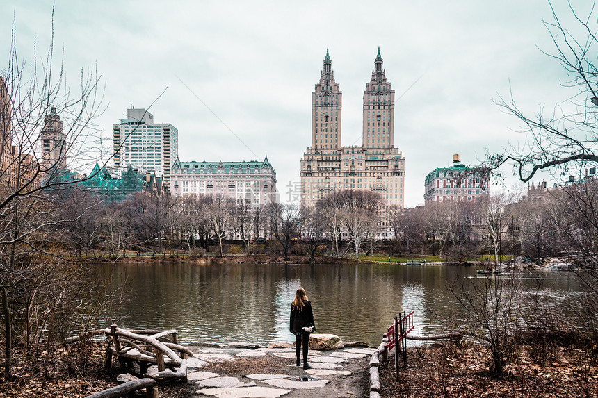 纽约市曼哈顿中央公园的树木河流和建筑物附近女孩照片图片
