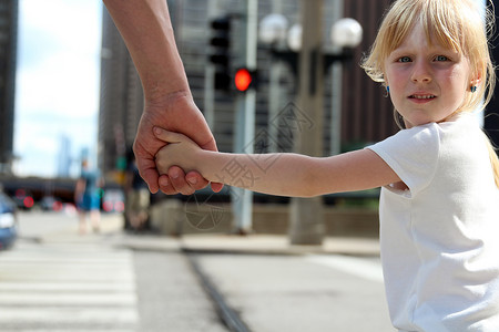 父亲在交通灯后拉着女儿孩子的手将孩子图片