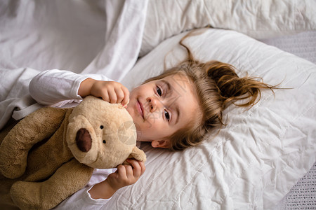 小女孩和柔软的玩具睡在床上小孩图片