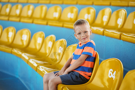 小男孩坐在一个空荡的体育场里图片