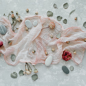 装饰成分包括干白色的郁金香和红玫瑰石头石块树叶花瓣和混凝土底部的图片