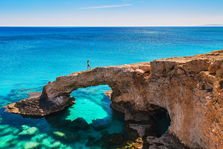 地中海塞浦路斯岛阿依纳帕卡沃格雷科和普罗塔拉斯附近美丽的天然岩石拱门上的女人传奇的桥梁爱好者令人惊叹的蓝绿色大海和阳图片