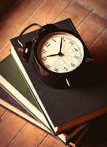 闹钟和棕色木制背景书籍的照片图片