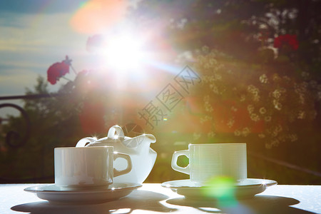 白色茶壶两个杯子和太阳花园派对图片