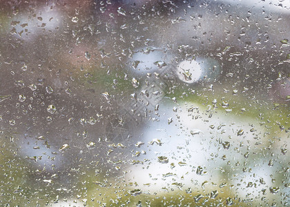 窗玻璃上的雨滴和模糊的城市背景图片