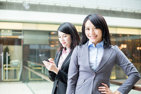 两名亚洲女商人在办公室外站岗一名图片