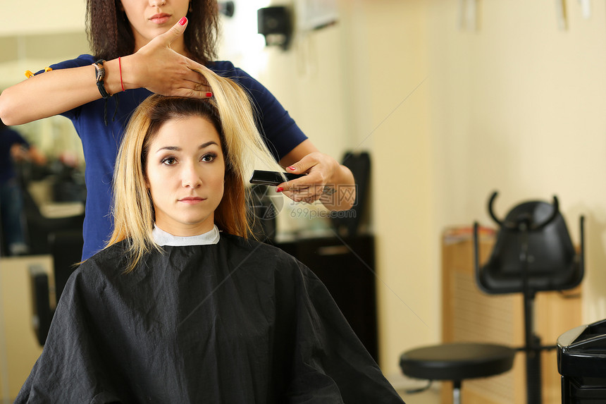 女理发师手拿着梳子和头发锁给漂亮的金发访客做发型角蛋白修复最新趋势新鲜理念新剪发图片