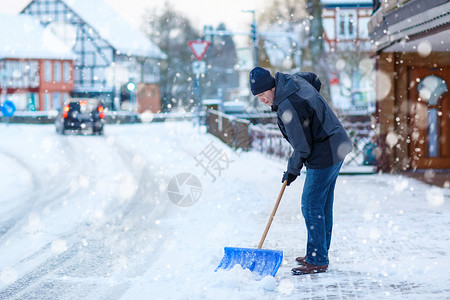 有雪铲的人在冬天打扫人行道欧洲的冬天穿着温暖图片