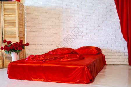 白色房间里铺着红色床单的床图片