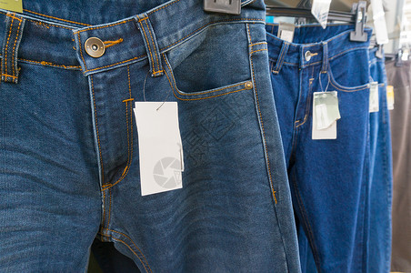 超市或大卖场零售店衣架上蓝色牛仔裤上的空白色图片