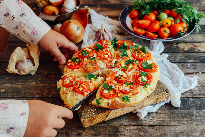 素食披萨比萨配西红柿葱和新鲜香草樱桃番茄木烤披萨自制玛格丽塔披萨坐在木制砧板上比萨配香蒜酱马苏里拉奶图片