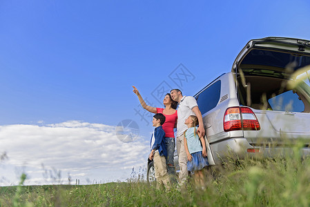 我们周围无与伦比的风景幸福的家庭站在田野里他的车旁图片