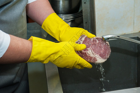戴手套在厨房水槽清洗和清洁肉类图片
