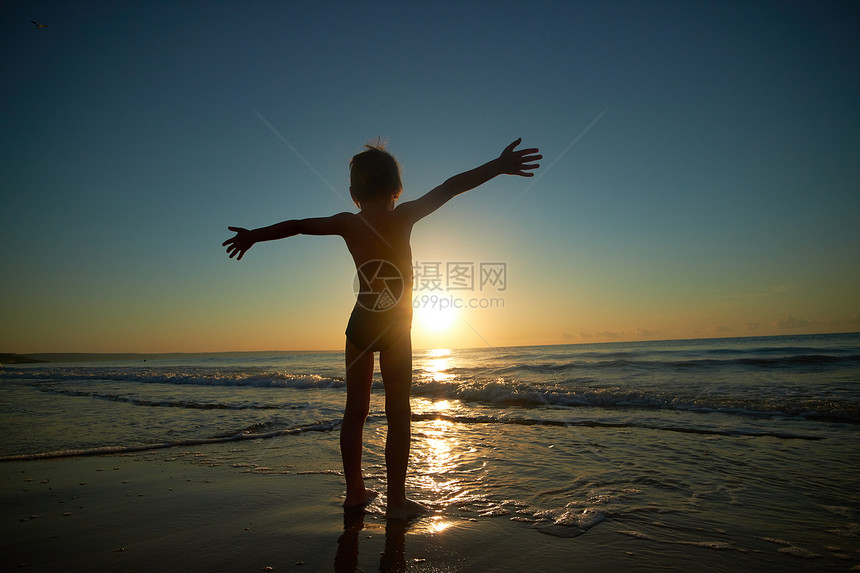 日落时在海边玩耍的小男孩图片